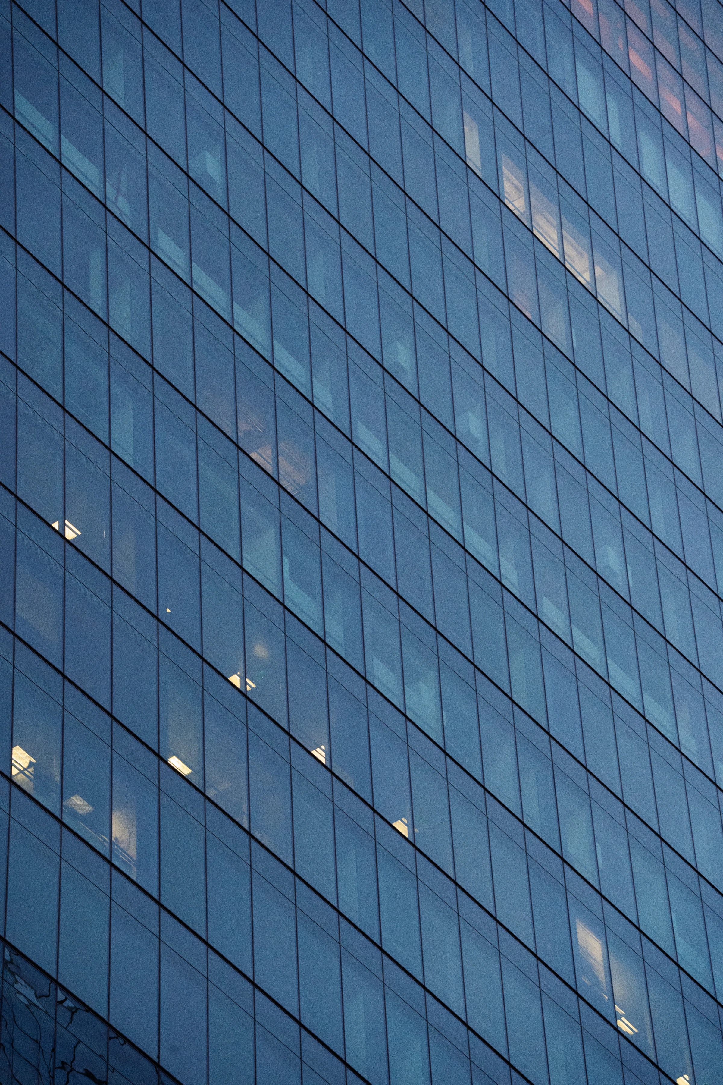Glass facade of a modern office building with reflective blue panels